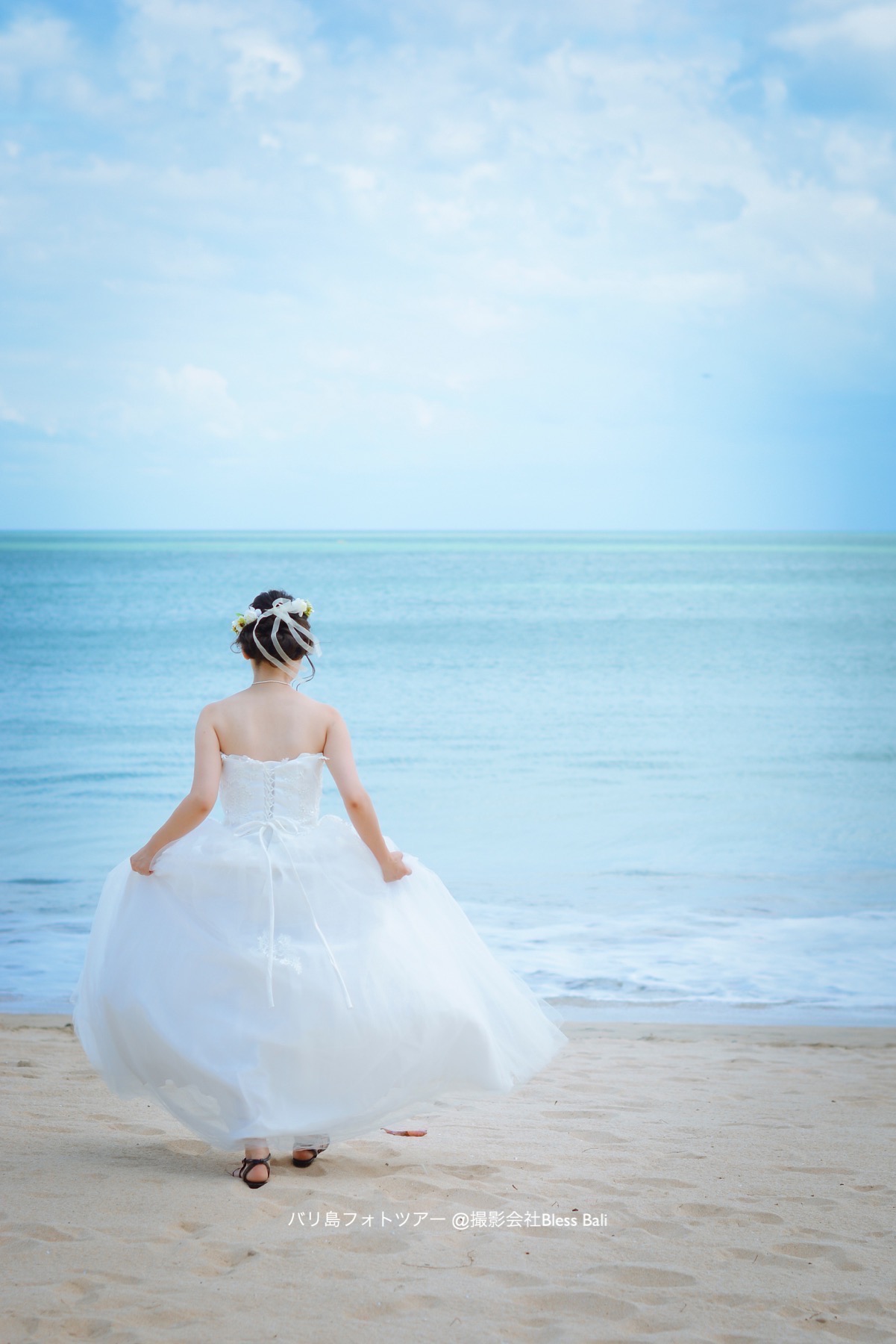 ドレスを持って海へと歩く花嫁様のソロショット