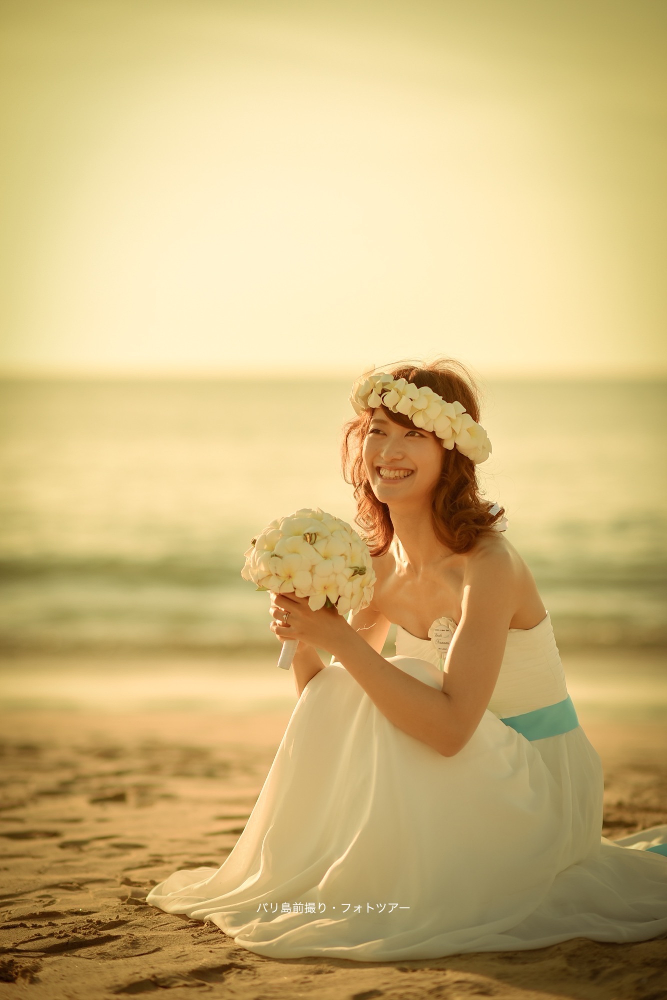 砂浜に座って微笑む花嫁